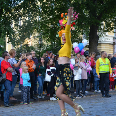 Kvinna i färgglada kläder dansar på gatan.