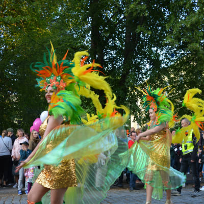 Kvinnor i färglada dräkter dansar på gatan.