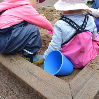 Några barn leker i en sandlåda.