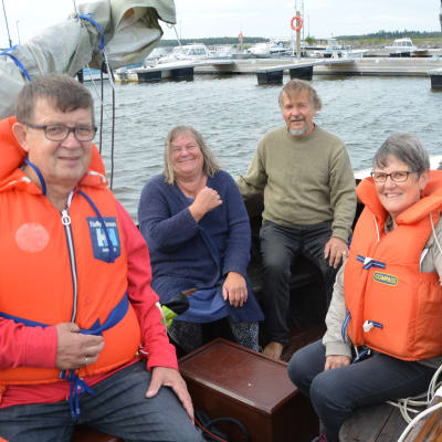 Fyra personer med flytväst i båt.