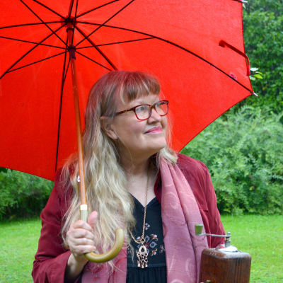 Ann-Sophie under ett rött paraply i regnet 