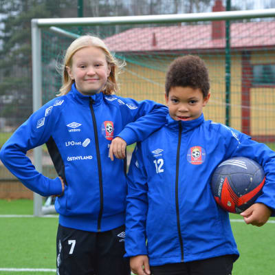 En flicka och en pojke på fotbollsplan.