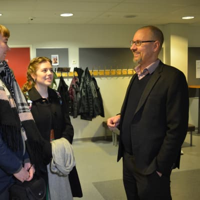 Kaksi abiturienttia, Sini Ojala ja Tiara Visser sekä apulaisrehtori Sami Peltonen keskustelevat koulun käytävällä.