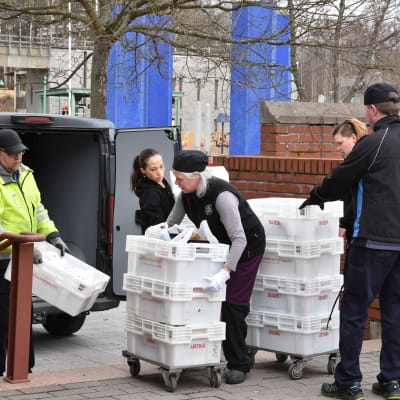 Personer lastar matvaror ur en paketbil. 