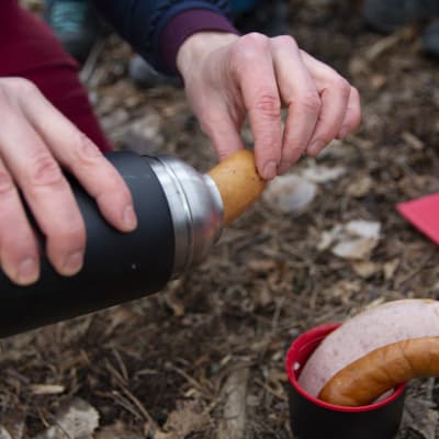 Esikypsytettyjä makkaranpaloja otetaan termospullosta, jossa myös kuumaa vettä. Koronapandemian aikana yleisiä grillauspaikkoja on syytä välttää.