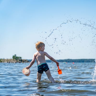 Barn leker i vattnet vid en badstrand i Nordsjö i Helsingfors den 25 juni 2020.