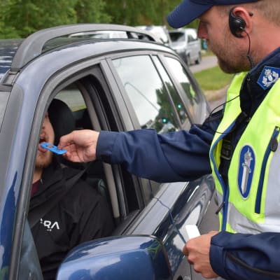 Poliisi tekee huumepikatestiä auton kuljettajalle.