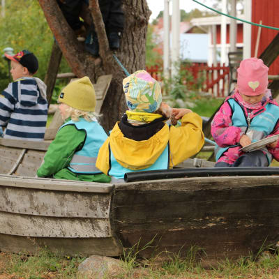 Barn sitter och leker i en eka på en dagisgård.