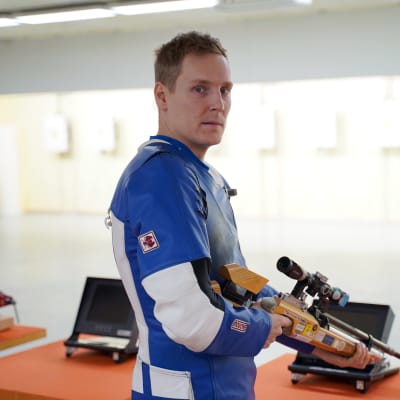 Niklas Hyvärinen står med ett gevär i händerna.