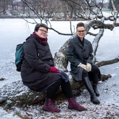 Kaksi yliopistotutkijaa istumassa puunrungolla.