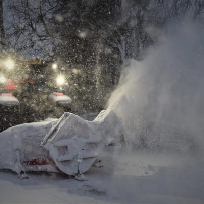 Traktor med snöplog som sprutar snö.