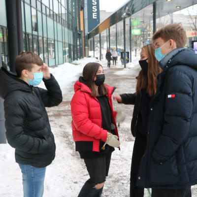 Fyra ungdomar står utanför ett köpcenter och pratar.