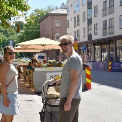 En kvinna och en man står på trottoaren på Kristinegatan. Mellan sig har de en barnvagn. 
