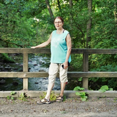 Agneta Ekbom står på en bro och håller i träräcket.