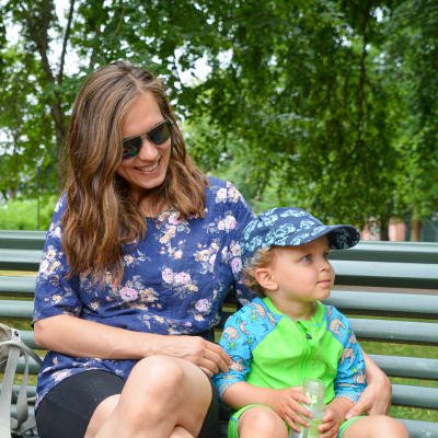 Emma Lavonen med sitt barn Aaron Lavonen på en bänk i en park. 