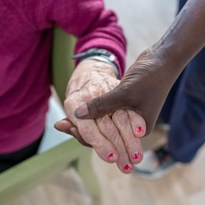 En skötare håller en pensionär om handen.