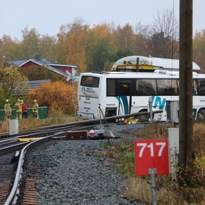 En buss ligger tvärs över en järnväg. Bakom bussen skymtar taket av en tågvagn.