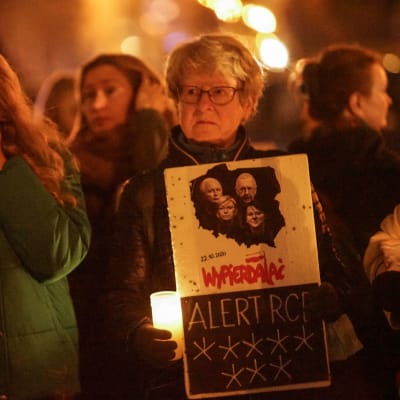 En kvinna som demonstrerar gråter, en annan håller i ett ljus och en skylt.