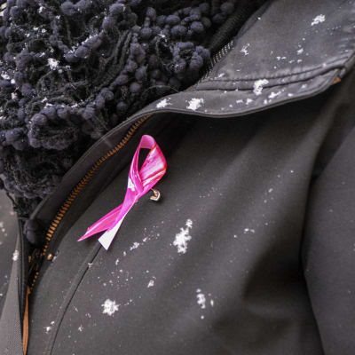 Rosa bandet-pins på en svart jacka. 