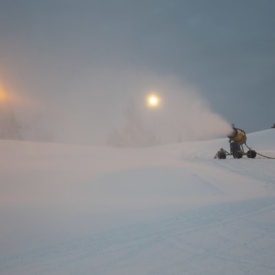 En snökanon blåser snö i en slalombacke.