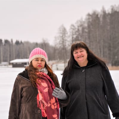 Två kvinnor i mörka vinterjackor poserar för kameran. Den ena ler, den andra ser mer orolig ut.