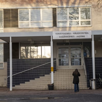 En person går mot ingången till en hälsocentral.