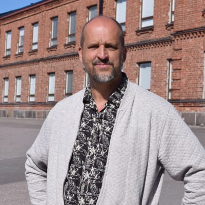 man framför tegelbyggnad och militärer