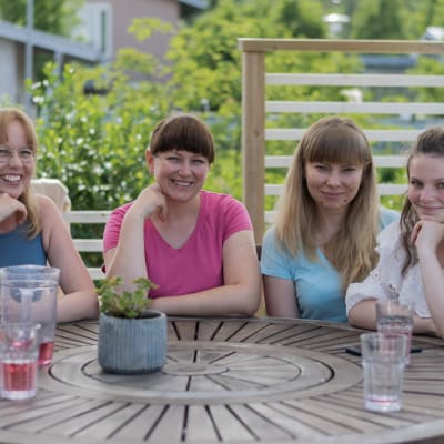 Minna Levälahti och de tre ukrainska kvinnorna som bor hos henne sitter runt ett bord på en terass.