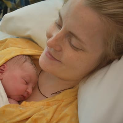 Veera Sillanpää pitää vastasynytyttä vauvaa sylissään TYKSin naistenklinikalla.