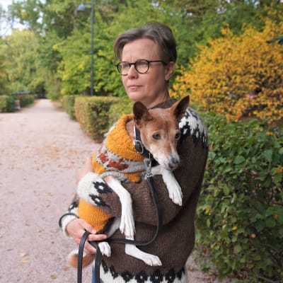 Porträtt på Sara Sundell som är ute på promenad i en park. Hon håller i sin hund. Både hon och hunden har tröjor på sig.