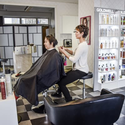 Vesna Gutic håller på att klippa håret på en kund i sin frisörsalong.