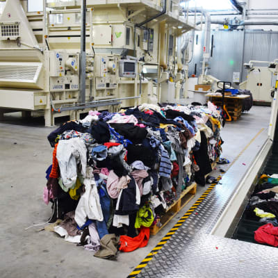 En stor hög med gamla kläder vid en produktionsanläggning som återvinner gamla textilier.