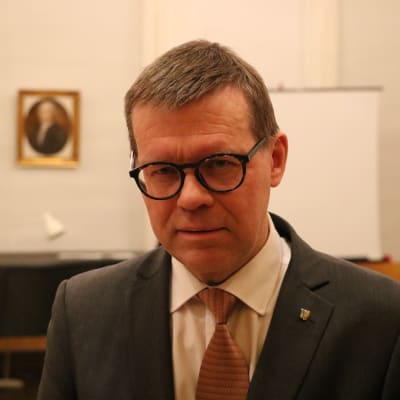 En man med glasögon står i en sal.