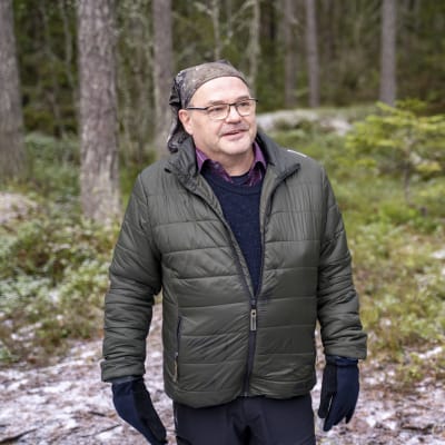 Man i skogen med grön jacka.