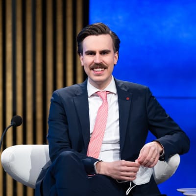 Matias Mäkynen, SDP, sitter leende framför en mikrofon.