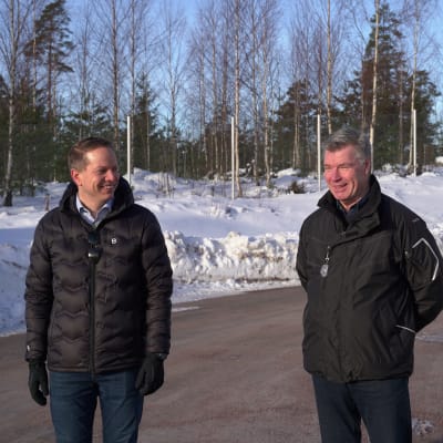 Två män utomhus i mörka jackor. I bakgrunden snö.