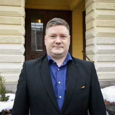 En man i skjorta och kavaj står framför Vasa stadshus.