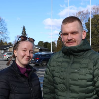 En man och en kvinna står vid en parkeringsplats.