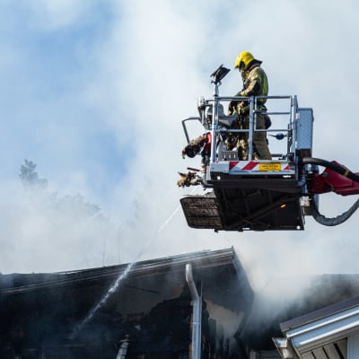 En brandman i skylift släcker ett brinnande hus