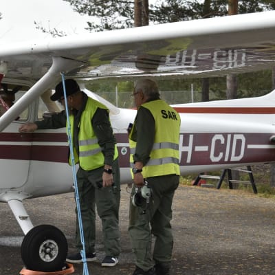 Kaksi vapaaehtoista katsoo vieressään olevaa Cessna-pienkonetta etsintä- ja pelastusharjoituksessa Sodankylässä.