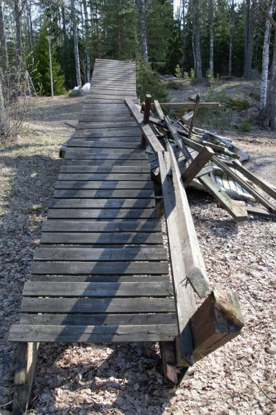 En lång trappa av trä som rivits ligger i en hög med annat bråte.