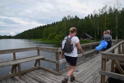 Bockabron i Kiisk i Pedersöre. Två personer med ryggsäckar och gummistövlar går över den smala träbron.