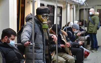 Människor på metron i Moskva. En man bär en gasmask, de andra munskydd.