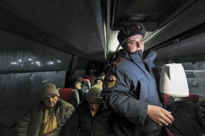 Venäläinen pelastustyöntekijä jakaa ihmisille teetä bussissa.