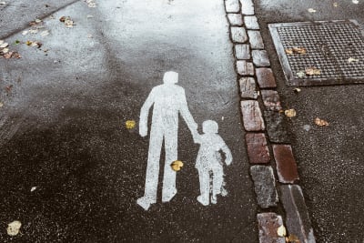 Ett foto av en symbol på en gångväg i Finland: En vuxen siluett som håller ett barn i handen.