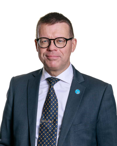 Porträttbild på Markku Lumio i mörkblå kostym och slips. 