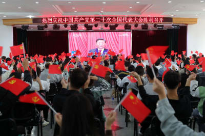 Människor som viftade med både flaggor då de tittade på öppningen av partikongressen i Huaibei, den 16 oktober. 