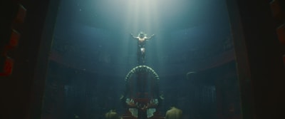 Strålar av ljus följer Namor (Tenoch Huerta) då han sjunker ner genom vattnet och snart landar på en tron av ett enormt fiskgap.