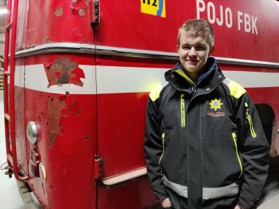 En man står vid en gammal brandbil, klädd i Pojo FBK:s jacka. Han heter Emil Nyman.
