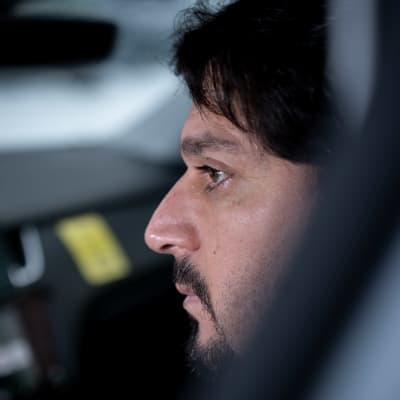 En taxiförare i närbild i sin bil.